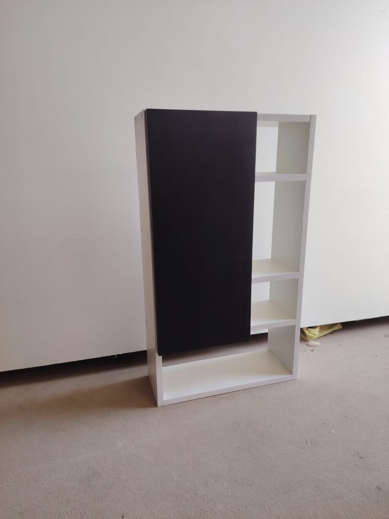 Estante blanco con puerta negra, foto en el taller